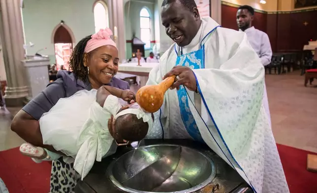 A child is baptised at the Roman Catholic Cathedral in Harare, Zimbabwe, Sunday, April 5, 2026. (AP Photo/Aaron Ufumeli)