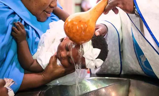A priest pours water over the head of a child during a baptism ceremony at the Roman Catholic Cathedral in Harare, Zimbabwe, Sunday, April 5, 2026. (AP Photo/Aaron Ufumeli)