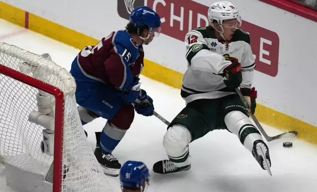 Minnesota Wild left wing Matt Boldy, right, collects the puck as Colorado Avalanche defenseman Jack Ahcan covers in the first period of Game 5 of an NHL Stanley Cup hockey second-round playoff series, Wednesday, May 13, 2026, in Denver. (AP Photo/David Zalubowski)