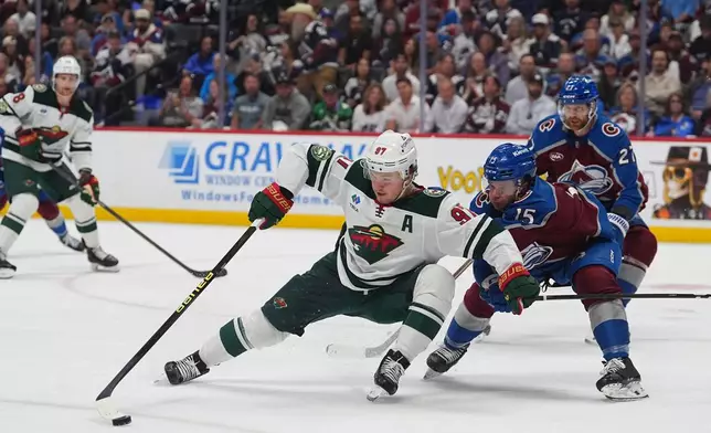 Minnesota Wild left wing Kirill Kaprizov, center, collects the puck as Colorado Avalanche defenseman Jack Ahcan covers in the second period of Game 5 of an NHL Stanley Cup hockey second-round playoff series, Wednesday, May 13, 2026, in Denver. (AP Photo/David Zalubowski)