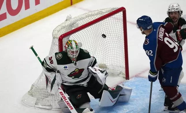 Minnesota Wild goaltender Jesper Wallstedt, left, allows a goal by Colorado Avalanche center Nathan MacKinnon as left wing Gabriel Landeskog looks on in the third period of Game 5 of an NHL Stanley Cup hockey second-round playoff series, Wednesday, May 13, 2026, in Denver. (AP Photo/David Zalubowski)
