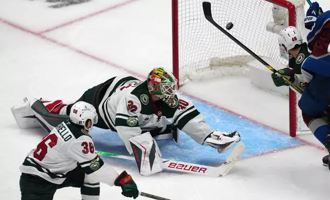 Minnesota Wild goaltender Jesper Wallstedt, center, misses a goal shot by Colorado Avalanche defenseman Brett Kulak as Minnesota right wing Mats Zuccarello, left, and defenseman Jared Spurgeon cover in overtime of Game 5 of an NHL Stanley Cup hockey second-round playoff series Wednesday, May 13, 2026, in Denver. (AP Photo/David Zalubowski)