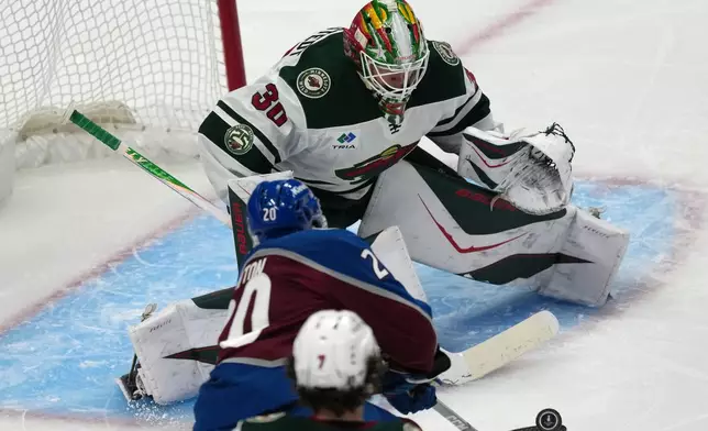 Colorado Avalanche center Ross Colton, front, puts a shot on Minnesota Wild goaltender Jesper Wallstedt in the first period of Game 5 of an NHL Stanley Cup hockey second-round playoff series, Wednesday, May 13, 2026, in Denver. (AP Photo/David Zalubowski)