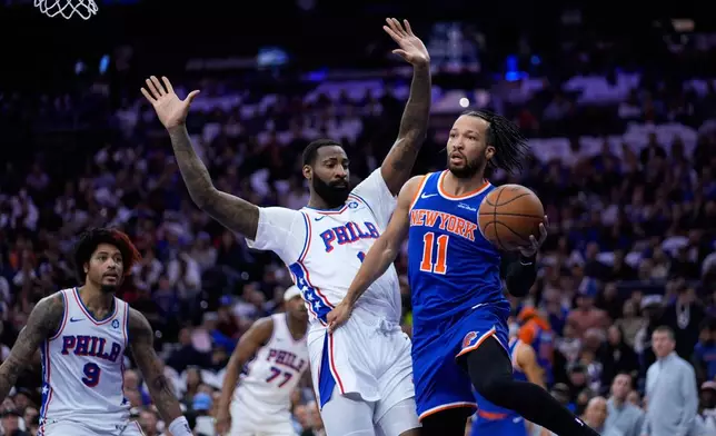 New York Knicks' Jalen Brunson, right, passes against Philadelphia 76ers' Andre Drummond during the first half of Game 3 in a second-round NBA basketball playoff series Friday, May 8, 2026, in Philadelphia. (AP Photo/Matt Slocum)