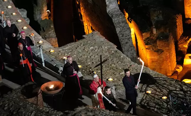 FILE - Pope Leo XIV carries a lightweight, 1.5-meter (5-foot) wooden cross during the Via Crucis, the torchlit Good Friday Stations of the Cross procession at the Colosseum in Rome, Friday, April 3, 2026, which symbolically retraces Jesus Christ's steps to his crucifixion on Calvary in Jerusalem. (AP Photo/Alessandra Tarantino, File)