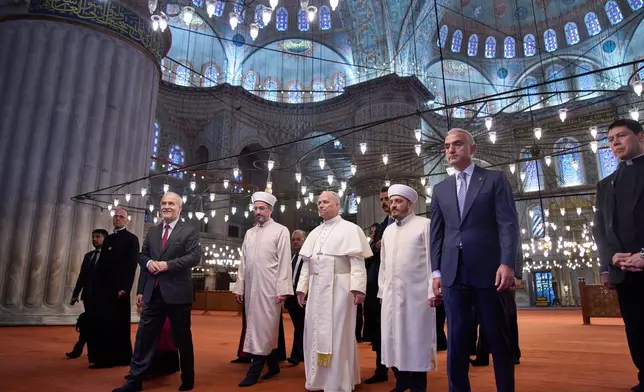 FILE - Pope Leo XIV, center, walks with Muezzin Musa Asgın Tunca, third from left, Istanbul's Mufti Emrullah Tuncel, fourth from left, the Imam of Mosque Sultanahmet Fatih Kaya, sixth from left, and Turkish Minister for Culture and Tourism Mehmet Nuri Ersoy, seventh from left, during a visit to the Mosque in Istanbul, Saturday, Nov. 29, 2025. (AP Photo/Domenico Stinellis, File)