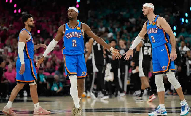 Oklahoma City Thunder guards Shai Gilgeous-Alexander (2) and Alex Caruso (9) high-five during the first half of Game 3 in the Western Conference finals NBA basketball playoffs series against the San Antonio Spurs Friday, May 22, 2026, in San Antonio. (AP Photo/Ashley Landis)