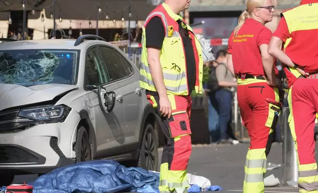 Rescue workers stand next to a damaged car that has crashed into several people in Leipzig, Germany, Monday, May 4, 2026. (Sebastian Willnow/dpa via AP)