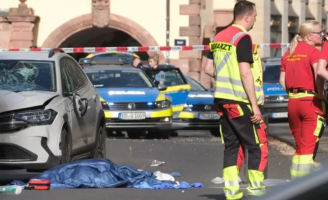 Rescue workers stand next to a damaged car that has crashed into several people in Leipzig, Germany, Monday, May 4, 2026. (Sebastian Willnow/dpa via AP)