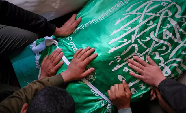 Palestinians place their hands on the body of Izz al-Din al-Haddad, the leader of Hamas' Qassam Brigades, draped in a Hamas flag during his funeral in Gaza City, Saturday, May 16, 2026. (AP Photo/Jehad Alshrafi)