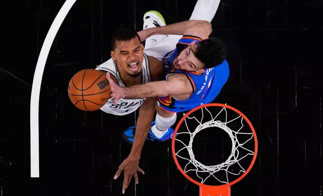 San Antonio Spurs forward Victor Wembanyama, left, scores against Oklahoma City Thunder center Chet Holmgren, right, during the first half in Game 4 in the Western Conference finals NBA basketball playoffs series in San Antonio, Sunday, May 24, 2026. (AP Photo/Eric Gay)