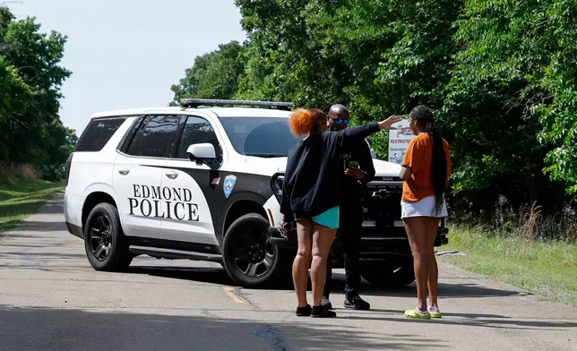Two women talk to an Edmond police officer blocking the entrance to Scissortail Campground at Arcadia Lake, Monday, May 4, 2026, in Edmond, Okla., after a shooting on Sunday evening. (AP Photo/Alonzo Adams)