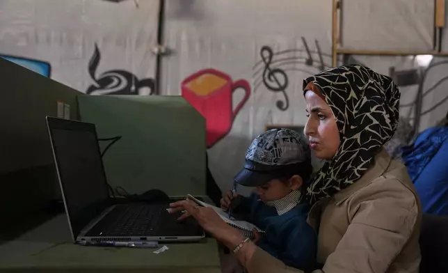 Palestinian graphic designer Reem Alkhateeb, 33, works on her computer next to her son at a coworking space in Khan Younis, southern Gaza Strip, March 9, 2026. (AP Photo/Abdel Kareem Hana)