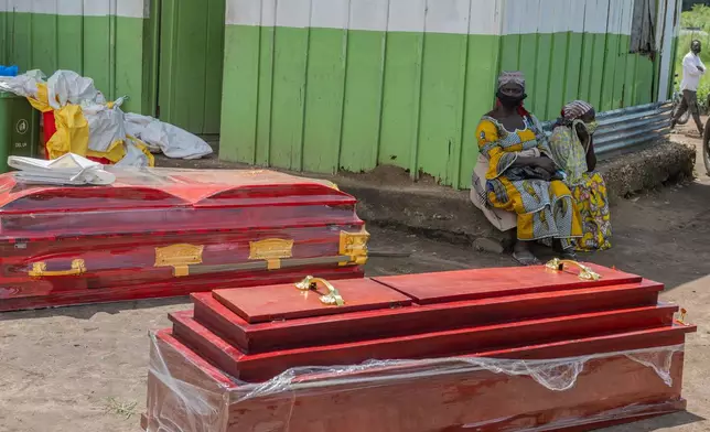 Two women sit beside coffins at a health center in Rwampara, Congo, Wednesday, May 20, 2026. (AP Photo/Moses Sawasawa)