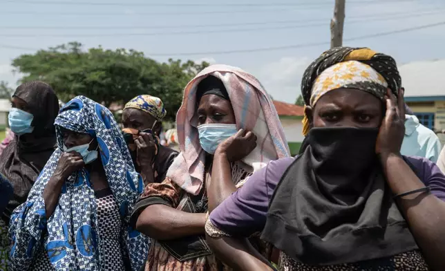 Relatives look on as people who died of Ebola are taken from a health center in Rwampara, Congo, Wednesday, May 20, 2026. (AP Photo/Moses Sawasawa)