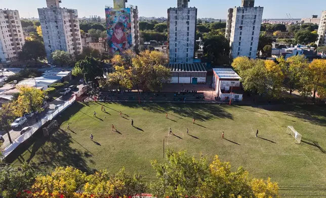 A mural of soccer star Lionel Messi covers the wall of a building as children play a match at the Grandoli club, where Messi played as a child in Rosario, Argentina, Saturday, May 2, 2026. (AP Photo/Rodrigo Abd)