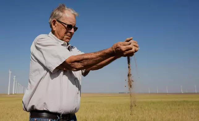 Farmer Orville Williams sifts powder dry soil as he checks the moisture in a drought-stressed wheat field Saturday, May 16, 2026, on his farm near Montezuma, Kan. (AP Photo/Charlie Riedel)