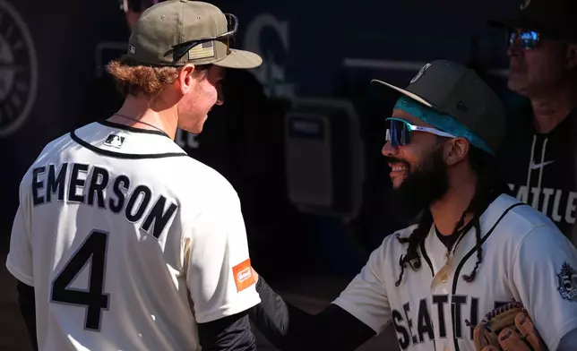 Seattle Mariners third baseman Colt Emerson (4) talks with shortstop J.P. Crawford, right, in the dugout before Emerson's major league debut against the San Diego Padres in a baseball game, Sunday, May 17, 2026, in Seattle. (AP Photo/Lindsey Wasson)