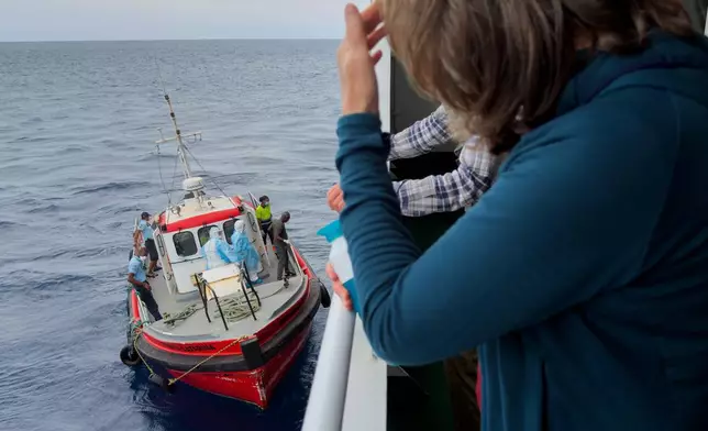Passengers on the the hantavirus-stricken cruise ship, MV Hondius, watch epidemiologists board the boat in Praia, during their voyage to Spain's port of Tenerife, May 6, 2026. (AP Photo)