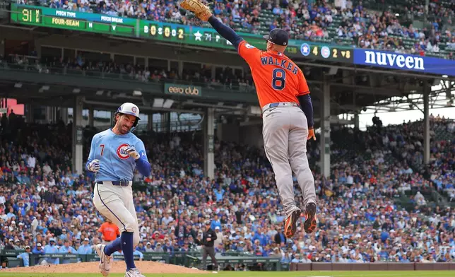 Houston Astros infielder Christian Walker jumps for the throw as Chicago Cubs' Dansby Swanson runs to first base during the eighth inning of a baseball game on Friday, May 22, 2026, in Chicago. (AP Photo/Melissa Tamez)