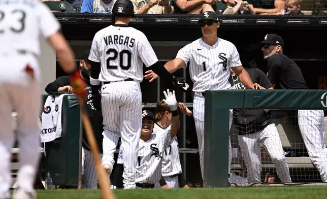 Chicago White Sox's Miguel Vargus (20) celebrates with manager Will Venable (1) at the dugout after scoring on Edgar Quero's sacrifice fly in the first inning of a baseball against the Detroit Tigers in Chicago, Saturday, May 30, 2026. (AP Photo/Paul Beaty)