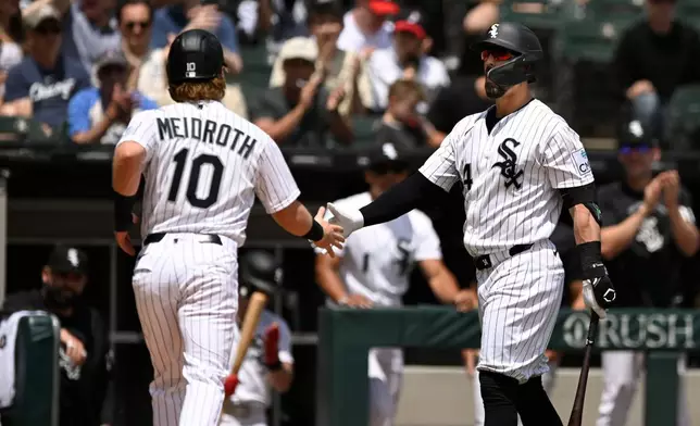 Chicago White Sox's Chase Meidroth (10) celebrates with Randal Grichuk, right, after scoring on a wild pitch during the first inning of a baseball against the Detroit Tigers in Chicago, Saturday, May 30, 2026. (AP Photo/Paul Beaty)