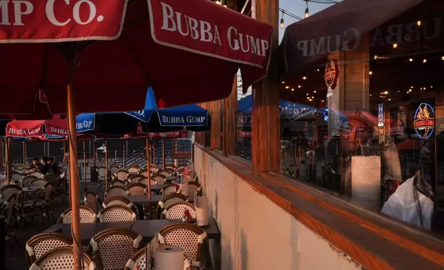 A diner looks out a restaurant window at sunset in Santa Monica, Calif., Wednesday, May 20, 2026. (AP Photo/Jae C. Hong)