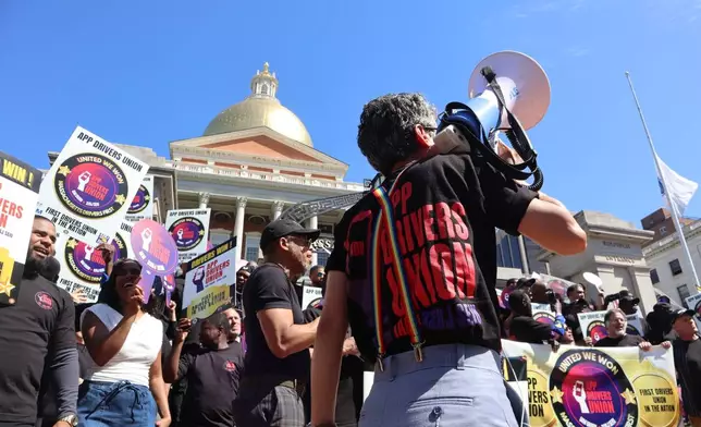 An organizer with the App Drivers Union speaks through a megaphone during a during a rally outside the Massachusetts State House after the App Drivers Union announced it had become the first certified union of rideshare drivers in the nation, on Tuesday, May 26, 2026, in Boston. (AP Photo/Leah Willingham)