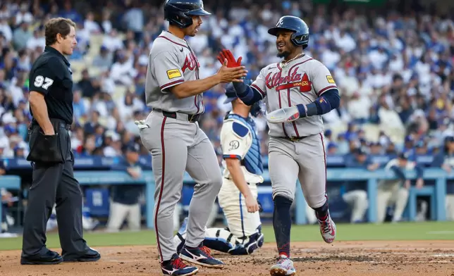 Atlanta Braves designated hitter Drake Baldwin, center left, greets teammate Ozzie Albies, center right, after they scored off a single hit by Braves' Matt Olson (not shown) during the second inning of a baseball game against the Los Angeles Dodgers, Saturday, May 9, 2026, in Los Angeles. (AP Photo/Caroline Brehman)