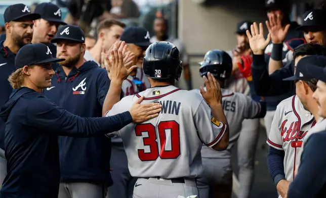 Atlanta Braves designated hitter Drake Baldwin (30) is greeted by teammates after scoring during the second inning of a baseball game against the Los Angeles Dodgers, Saturday, May 9, 2026, in Los Angeles. (AP Photo/Caroline Brehman)