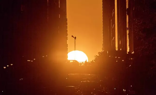 The setting sun is framed between buildings during Manhattanhenge along 42nd Street, Thursday, May 28, 2026, in New York. (AP Photo/Andres Kudacki)