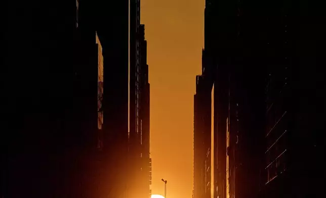 The setting sun is framed between buildings during Manhattanhenge along 42nd Street, Thursday, May 28, 2026, in New York. (AP Photo/Andres Kudacki)