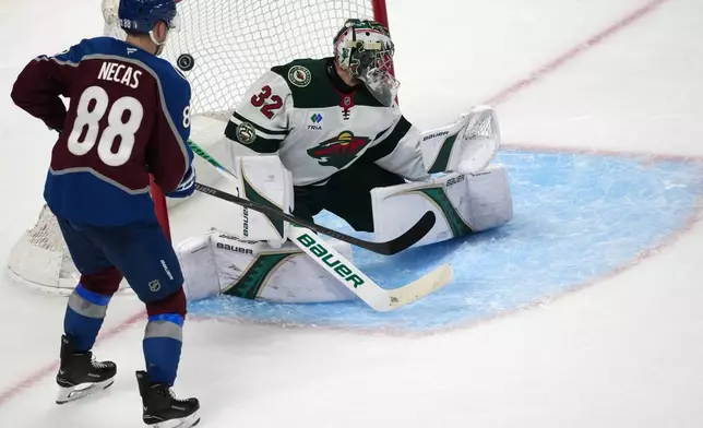 Colorado Avalanche center Martin Necas, left, looks on as Minnesota Wild goaltender Filip Gustavsson allows a goal by Colorado center Nathan MacKinnon in the third period of Game 2 of an NHL hockey Stanley Cup second-round playoff series Tuesday, May 5, 2026, in Denver. (AP Photo/David Zalubowski)