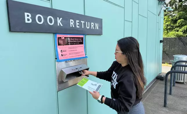 A voter drops off their ballot at a library in Portland, Ore. serving as a ballot dropbox site as Oregon held primary elections on May 19, 2026. (AP Photo/Claire Rush)