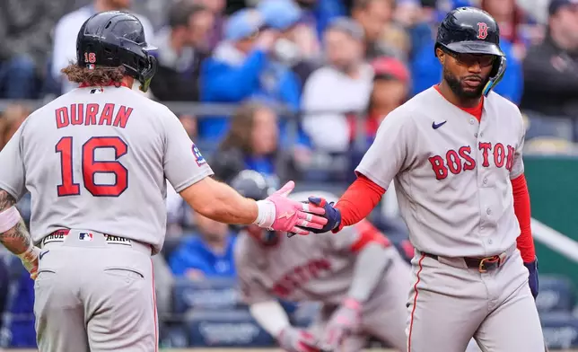 Boston Red Sox's Jarren Duran (16) celebrates with Andruw Monasterio after scoring on a single by Willson Contreras during the first inning of a baseball game against the Kansas City Royals, Tuesday, May 19, 2026, in Kansas City, Mo. (AP Photo/Charlie Riedel)