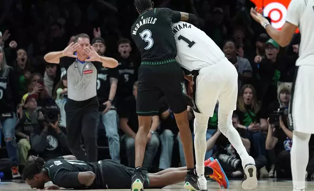 Minnesota Timberwolves center Naz Reid (11) falls to the court after he was fouled by San Antonio Spurs forward Victor Wembanyama (1) as he and forward Jaden McDaniels (3) battled for a rebound during the first half of Game 4 of a NBA basketball second-round playoff series in Minneapolis, Sunday, May 10, 2026. (AP Photo/Abbie Parr)