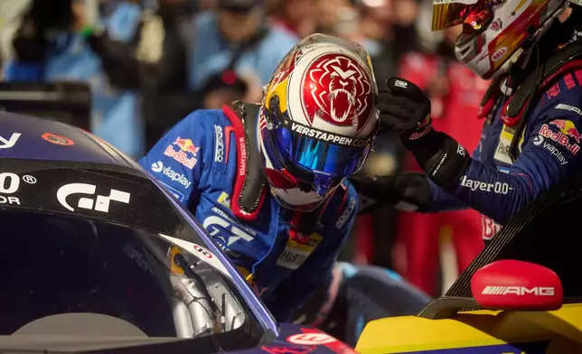 Daniel Juncadella, right, helps his teammate Max Verstappen to get into the car during a pit stop the Nurburgring 24-hour auto race in Nurburg, Germany, Sunday, May 17, 2026. (Thomas Frey/dpa via AP)