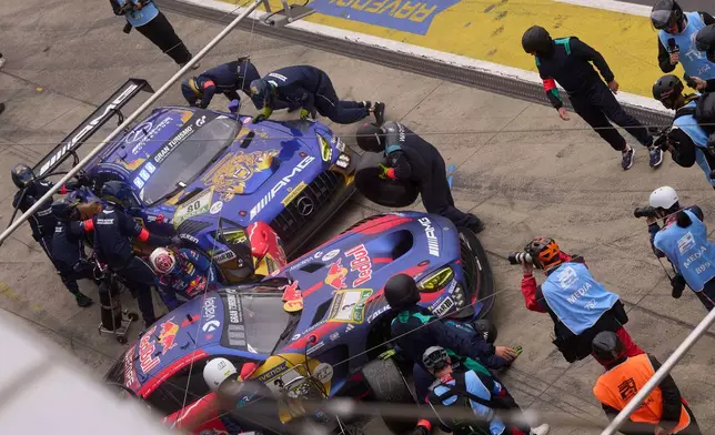 The pit crew works on the leading Max Verstappen's Mercedes AMG GT3 car, right, as it completes a pit stop at the same time as the second-placed Mercedes-AMG Team RAVENOL with Germany's Maro Engel, Germany's Luca Stolz, Germany's Fabian Schiller and Germany's Maxime Martin, during the Nurburgring 24-hour auto race in Nurburg, Germany, Sunday, May 17, 2026. (Thomas Frey/dpa via AP)