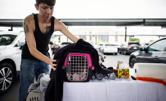 An evacuee gather their pets and belongings at the John F. Kennedy High School in La Palma, Calif., on Sunday, May 24, 2026. (AP Photo/Ethan Swope)