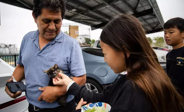 Oscar Bello, who evacuated Anaheim with his pets, shows them off at the John F. Kennedy High School in La Palma, Calif., on Sunday, May 24, 2026. (AP Photo/Ethan Swope)