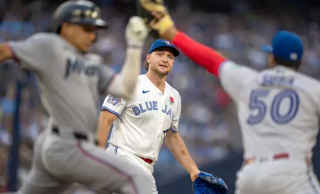 Toronto Blue Jays pitcher Trey Yesavage, center, watches as his throw to first baseman Lenyn Sosa (50) puts out Miami Marlins' Javier Sanoja, left, during first-inning baseball game action in Toronto, Monday May 25, 2026. (Frank Gunn/The Canadian Press via AP)