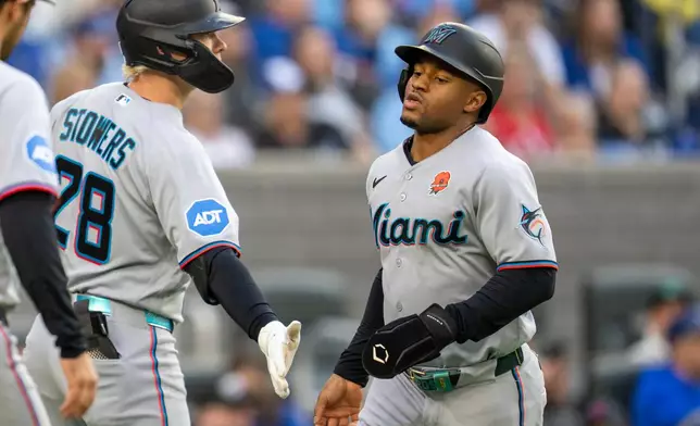 Miami Marlins' Xavier Edwards, right, is congratulated by Kyle Stowers (28) after scoring against the Toronto Blue Jays during first-inning baseball game action in Toronto, Monday May 25, 2026. (Frank Gunn/The Canadian Press via AP)
