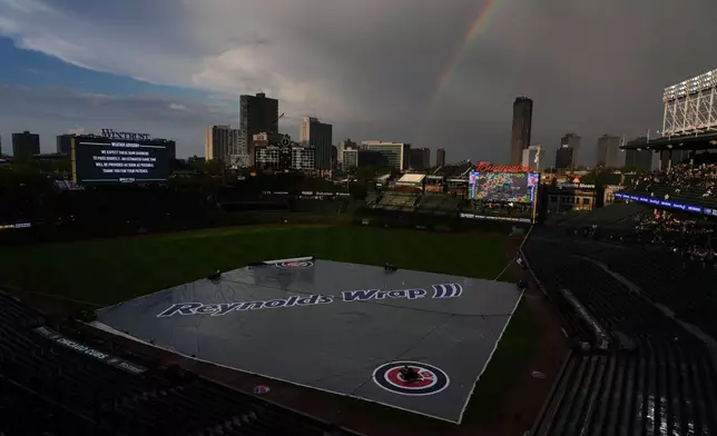 A rainbow occurs while a tarp covers the infield during a rain delay before a baseball game between the Cincinnati Reds and the Chicago Cubs in Chicago, Monday, May 4, 2026. (AP Photo/Nam Y. Huh)