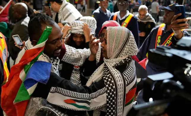 Ebrahim Peters, left, an activist embraces his family member after returning home at OR Tambo International Airport, in Johannesburg, South Africa, Saturday, May 23, 2026. (AP Photo/Themba Hadebe)