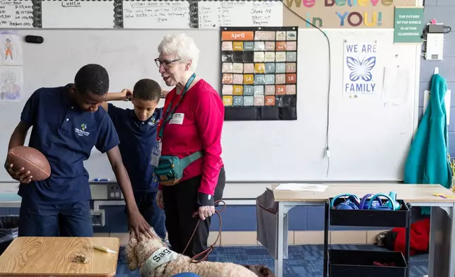 Shane Jackson, left, pets Sage, a therapy dog, while chatting with Sage's owner, Linda Buchs-Hammonds, at Valley View Elementary School on April 29, 2026, in Columbia Heights, Minn. (Ellen Schmidt/MinnPost via AP)