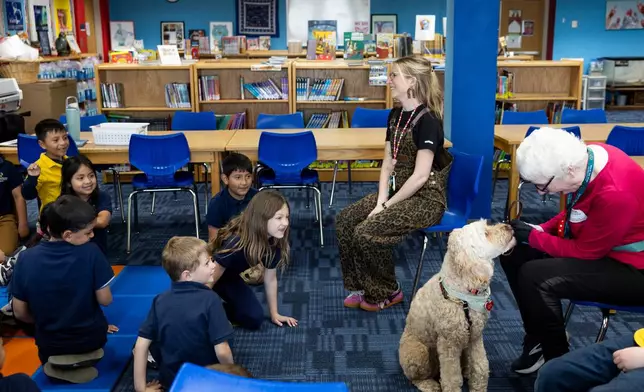 School social worker Nicole Herje, center, therapy dog Sage and Sage's owner Linda Buchs-Hammonds sit in on a class in the library at Valley View Elementary School on April 29, 2026, in Columbia Heights, Minn. (Ellen Schmidt/MinnPost via AP)