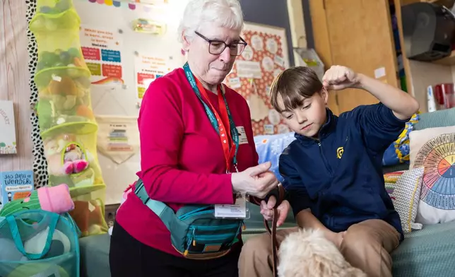 Linda Buchs-Hammonds, left, shows fifth grader Miles how to ask Sage, a therapy dog, to sit at Valley View Elementary School on April 29, 2026, in Columbia Heights, Minn. (Ellen Schmidt/MinnPost via AP)