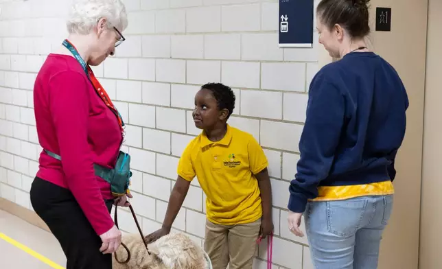 Second grader Samuel stops in the hallway to pet Sage, a therapy dog who visits Valley View Elementary weekly with her owner Linda Buchs-Hammonds, on April 29, 2026, in Columbia Heights, Minn. (Ellen Schmidt/MinnPost via AP)