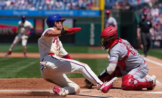 Philadelphia Phillies' Trea Turner scores past Cincinnati Reds catcher P.J. Higgins during the first inning of a baseball game, Wednesday, May 20, 2026, in Philadelphia. (AP Photo/Matt Rourke)