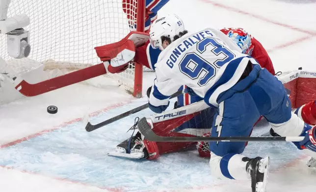 Tampa Bay Lightning's Gage Goncalves (93) scores against Montreal Canadiens goaltender Jakub Dobes, bottom, during overtime of Game 6 in the first round of an NHL hockey Stanley Cup playoff series in Montreal, Friday, May 1, 2026. (Christinne Muschi/The Canadian Press via AP)